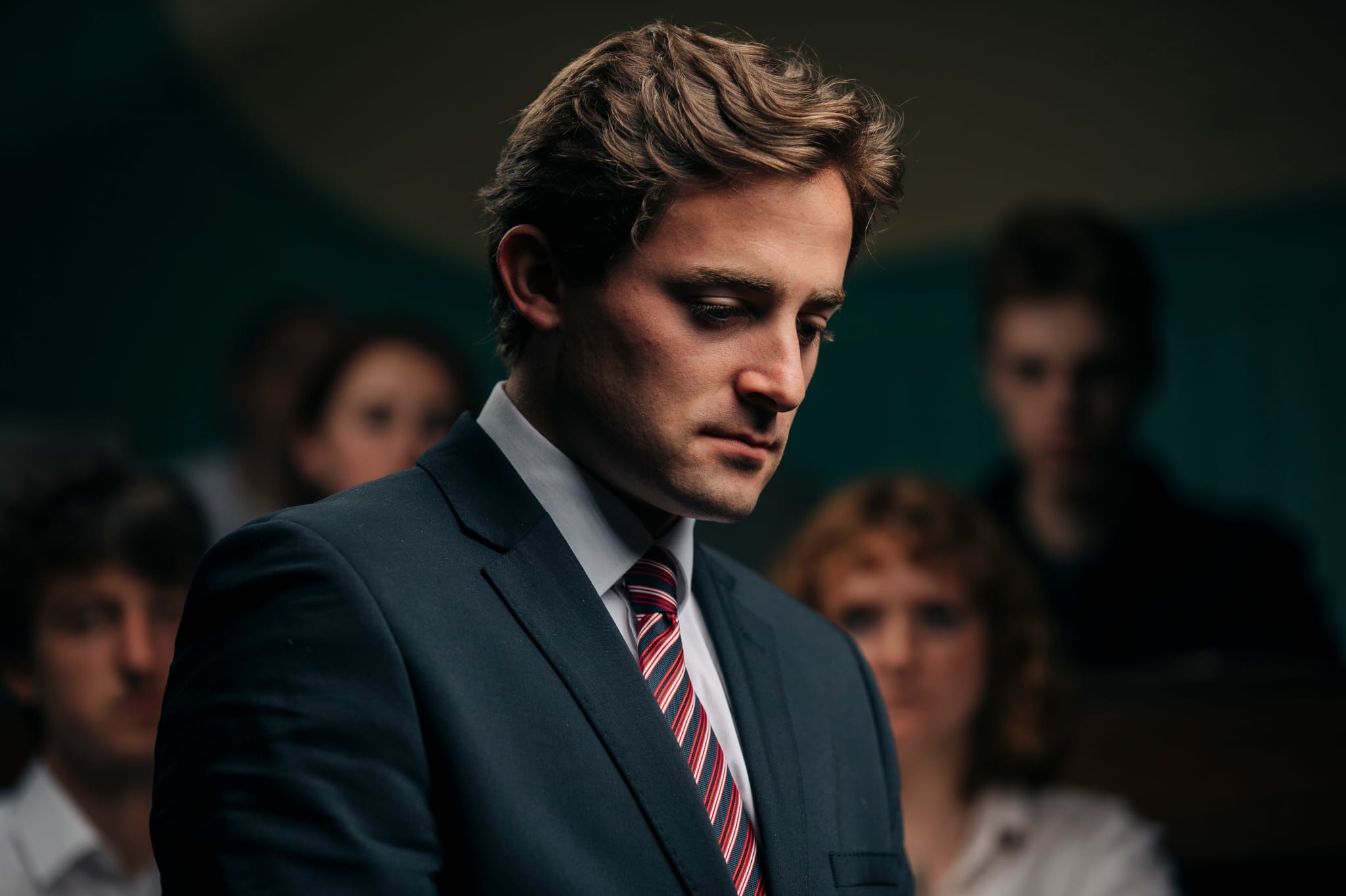 Benjamin Sumrie in character looking down in a smart suit